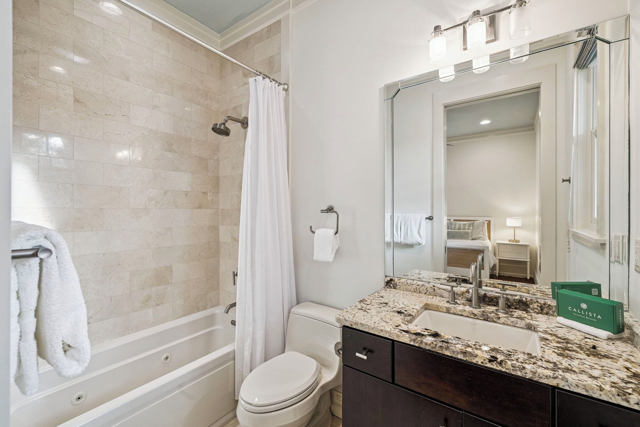 A modern bathroom with a bathtub, toilet, and vanity.