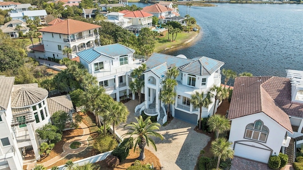Un quartier résidentiel avec des maisons situées près d’un lac, comprenant une maison principale dotée d’une grande allée et d’une piscine.