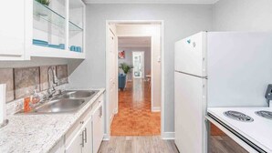 A modern kitchen with white cabinetry, a granite countertop, a stainless steel sink, and a built-in stove. - 1BR Condo w/City Views by Peachtree (Atlanta)