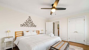 A neatly arranged bedroom with a bed, nightstands, a suitcase, and a ceiling fan. - Downtown Atlanta Condo  Walk to Everything (Atlanta)