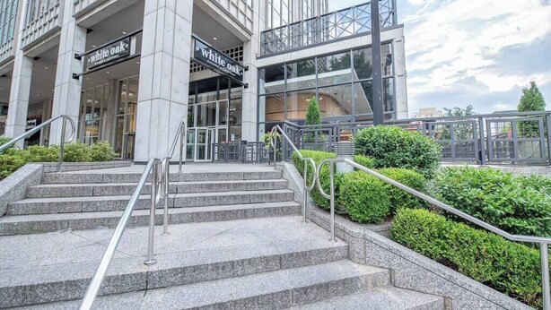 Un edificio moderno con facciata in vetro, una scala che conduce all'ingresso e un cartello con scritto 'White Oak'.