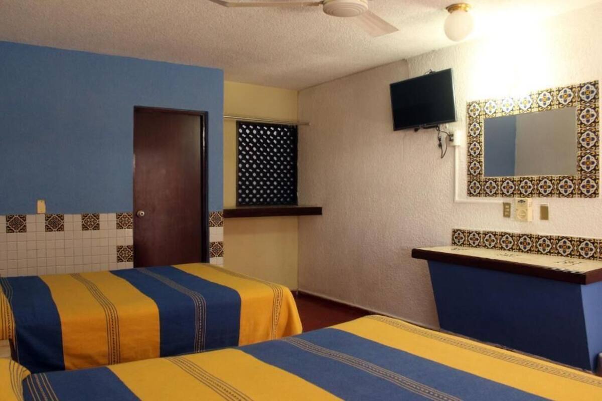 A hotel room with two beds, a TV, a mirror, and a small desk.