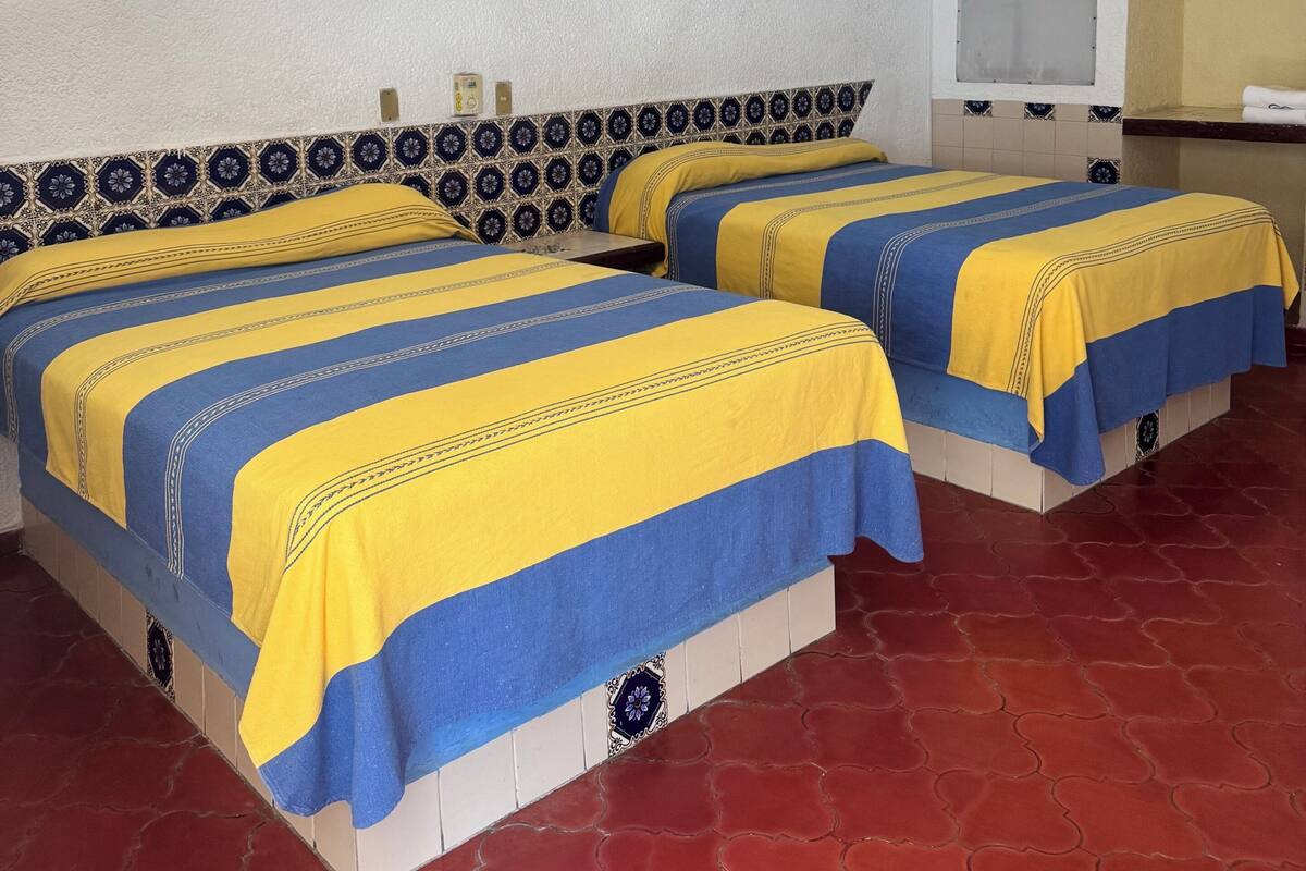 A hotel room with two beds, a ceiling fan, a window, and a tiled floor.