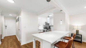Una cocina moderna con armarios blancos, una isla central y taburetes de bar.