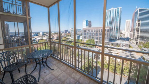 A balcony with a table and chairs, offering a view of a cityscape with various buildings. - Short walk to Centennial Park and Mercedes Benz (Atlanta)