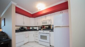 A compact kitchen with white cabinets, a built-in microwave, a stove, and a refrigerator. - Short walk to Centennial Park and Mercedes Benz (Atlanta)