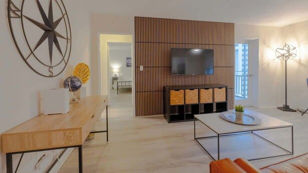 A modern living room with a wooden partition, a flat-screen TV, a coffee table, and a sofa. - Bright Downtown Retreat w/ Full Kitchen (Atlanta)