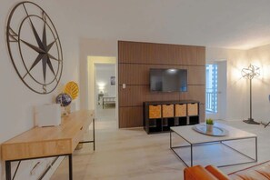 A modern living room with a wooden partition, a flat-screen TV, a coffee table, and a sofa. - Bright Downtown Retreat w/ Full Kitchen (Atlanta)