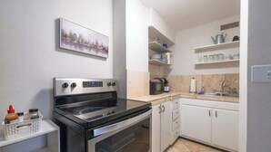 A modern kitchen with a stainless steel stove, white cabinets, and a tiled backsplash. - Bright Downtown Retreat w/ Full Kitchen (Atlanta)