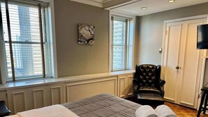 A hotel room with a large bed, a chair, a TV, and a window with blinds. - Cozy High-Rise Condo Near AmericasMart (Atlanta)