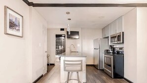 Een moderne keuken met witte kasten, roestvrijstalen apparatuur en een centraal eiland met een barkruk.