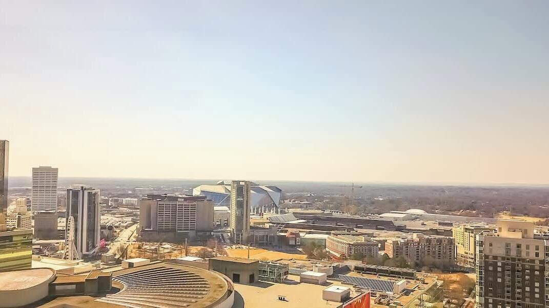 A cityscape with modern buildings, including a distinctive curved structure and a circular plaza.