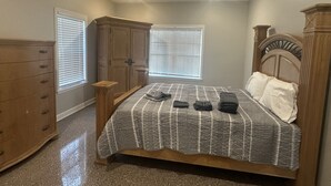 Un dormitorio con cama, cómoda y ventanas.