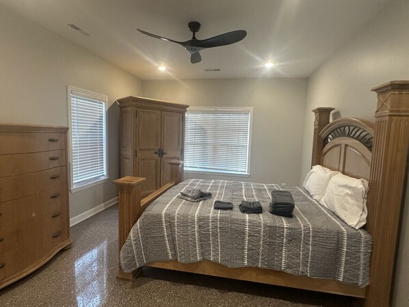 A bedroom with a bed, dresser, and windows.