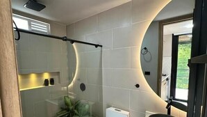 Une salle de bain moderne avec une douche à parois de verre, des toilettes blanches et un grand lavabo.