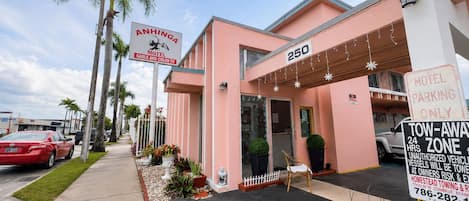 A pink motel with a sign indicating it offers cable and color TV.