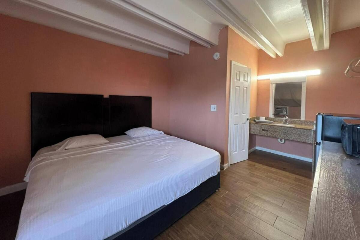 A bedroom with a bed, a small kitchenette, and a door.