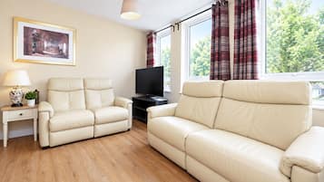 A living room with two beige sofas, a television, a lamp, and a framed picture on the wall.