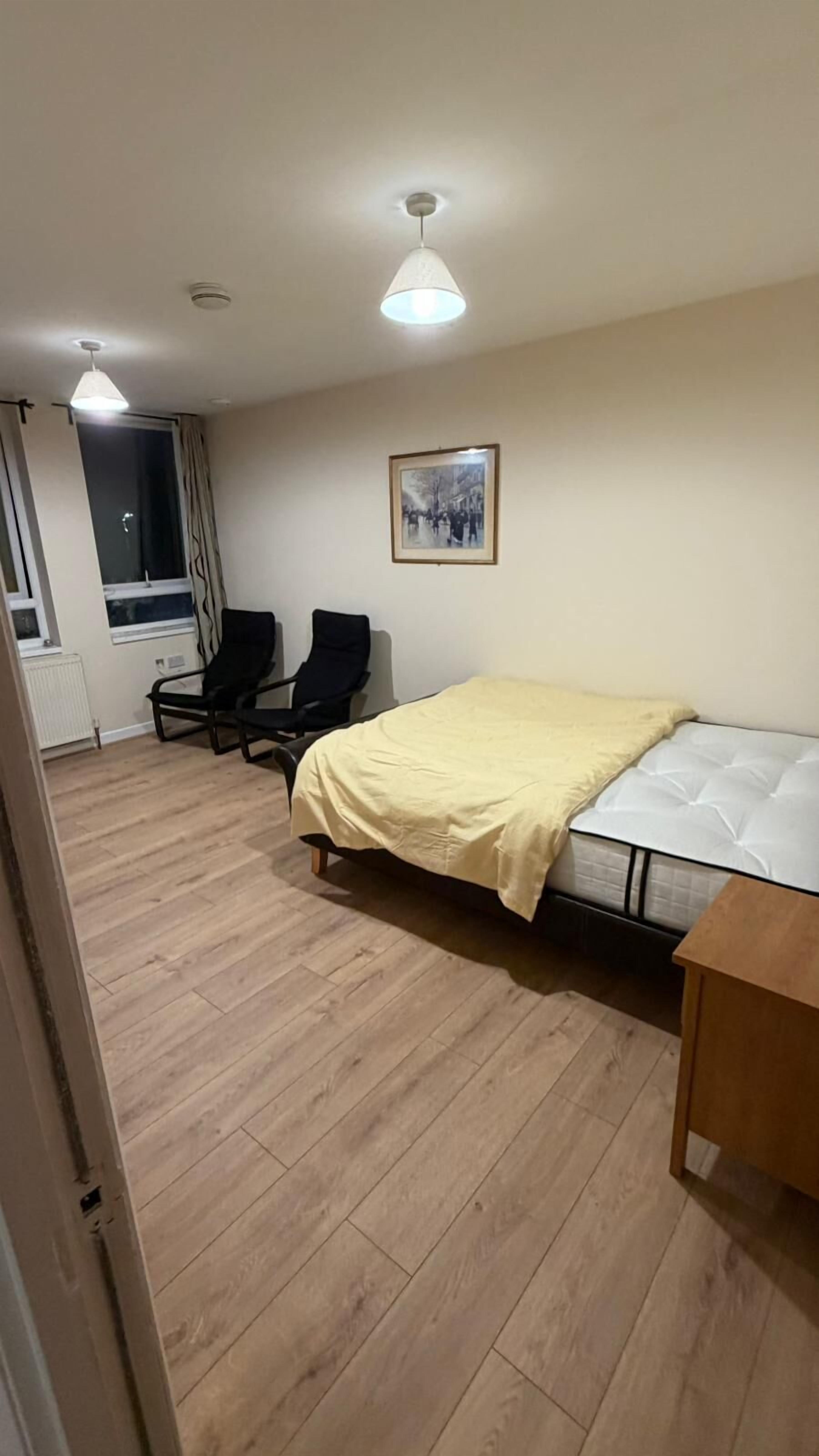 A bedroom with a bed, a chair, a desk, and a picture on the wall.