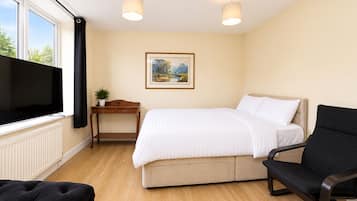 A hotel room with a bed, a desk, a chair, a TV, and a window.