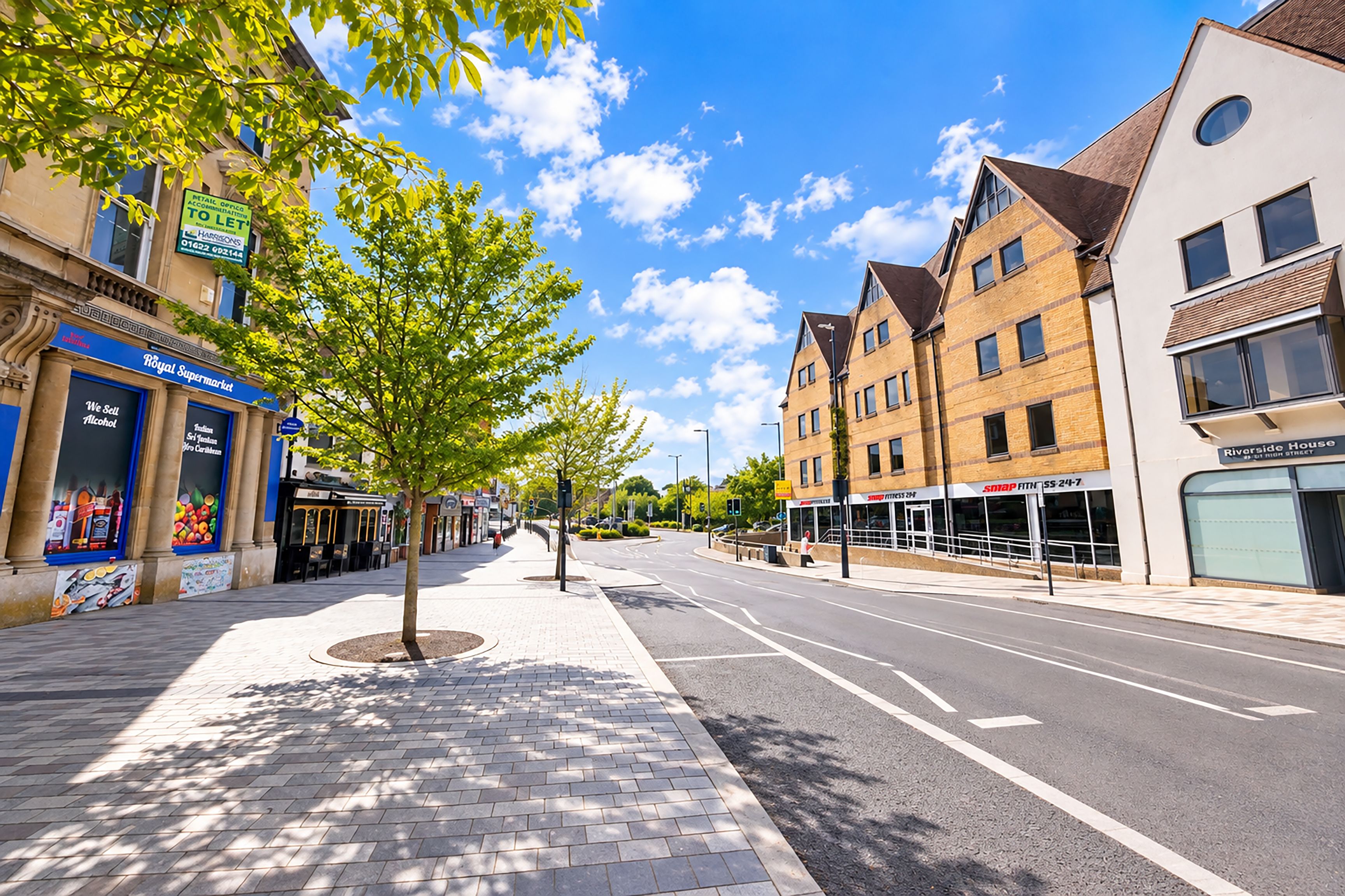 A street with buildings, a sidewalk, and a tree.