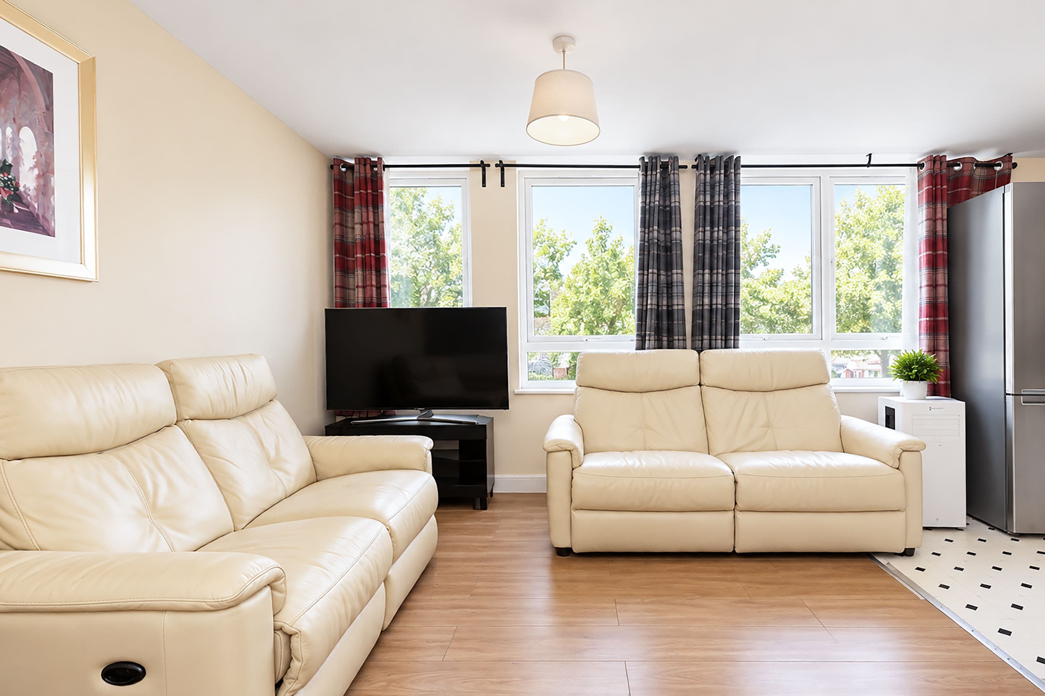 Una sala de estar con sofá, sillón reclinable, televisor de pantalla plana y refrigerador.