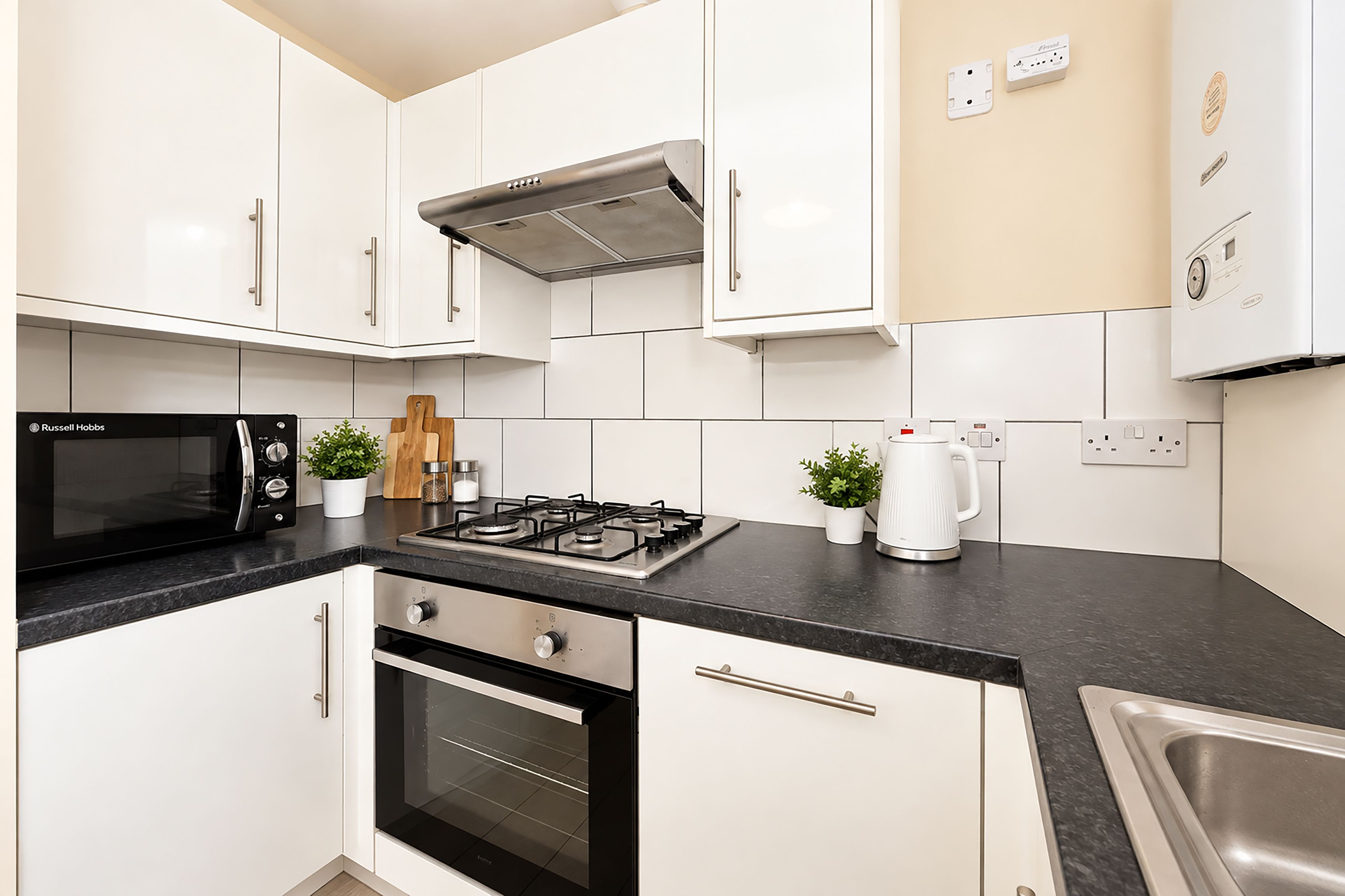 A modern kitchen with white cabinets, a black microwave, a gas stove, and a built-in oven.