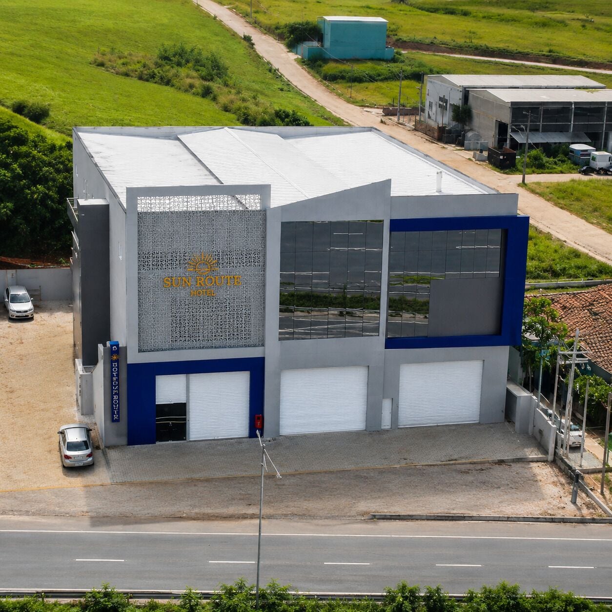 A modern building with a large sign for 'Sun Route Hotel' and a parking area with a few cars.