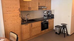 Una cocina compacta con armarios de madera, un lavamanos, una estufa y una cafetera.