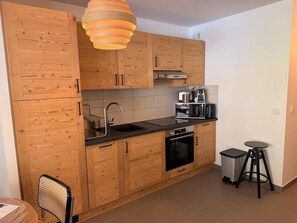 Eine kleine Küche mit Holzschränken, einem Spülbecken, einem Herd und einer Kaffeemaschine.