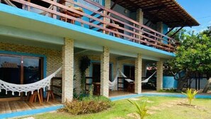 A two-story building with a balcony, a hammock, and a well-maintained lawn. - Pousada Manga Azul (Barra de Camaratuba)
