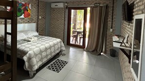 A room with a bed, a desk, a TV, and a window with curtains. - Pousada Manga Azul (Barra de Camaratuba)