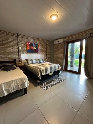 Une chambre avec deux lits, une grande fenêtre donnant sur un beau paysage et un luminaire au plafond.