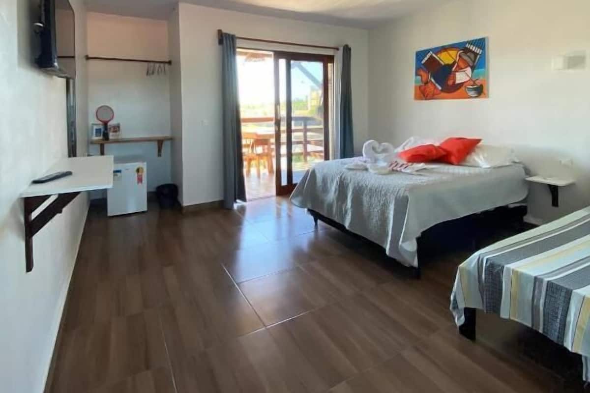 A hotel room with a bed, a desk, a TV, and a painting on the wall.