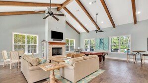 Un salón espacioso con chimenea, vigas de madera y ventanas grandes.