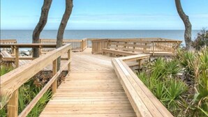 Una pasarela de madera que lleva a una playa con una vista despejada del océano.
