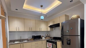 Et moderne køkken med en central ø, rustfrit stål hvidevarer og en indbygget loftlampe.