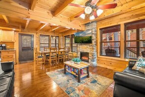 A spacious living area with a fireplace, wooden ceiling, and large windows. - Charming Chalet Getaway in Prime Location, with Hot Tub & Pools (Pigeon Forge)