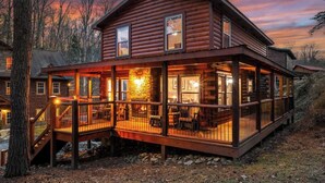 Eine Blockhütte mit einer Terrasse und einem Sitzbereich im Freien, umgeben von Bäumen.