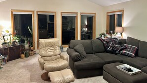 A living room with a leather recliner, a dark sofa, and a ceiling fan. - Views for Days! Flathead Lake Retreat 1 mile to Downtown (Polson)