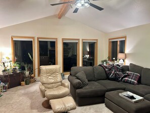 Ein Wohnzimmer mit einem Ledersessel, einem dunklen Sofa und einem Deckenventilator.