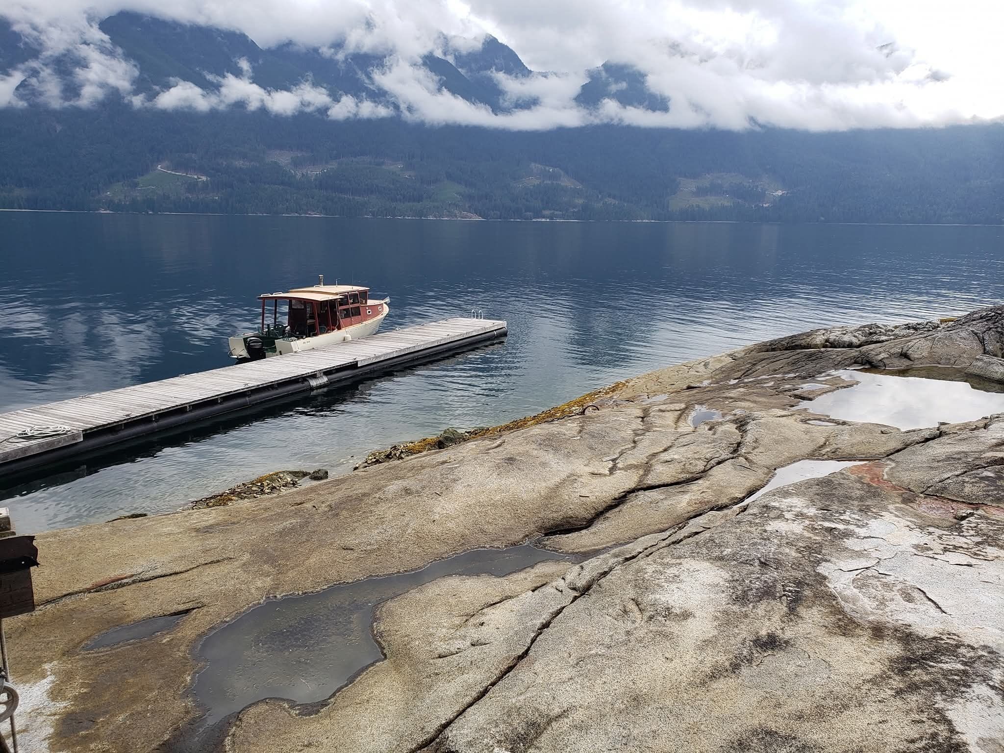 Eine Anlegestelle, die in einen stillen See führt, mit einem Boot, das am Ende vertäut ist.