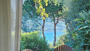 A wooden table and chairs in a garden with a view of the sea. - Villa Serena by the sea (MARACALAGONIS)