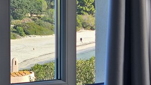 A window view of a beach with a forested hillside in the background. - Villa Serena by the sea (MARACALAGONIS)