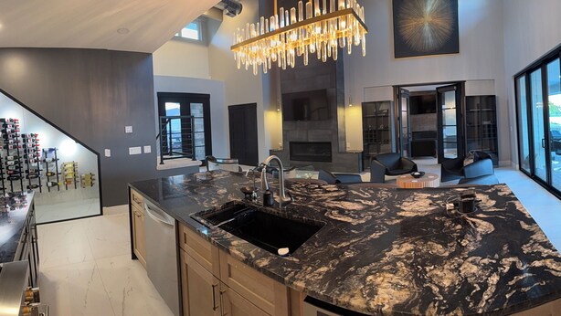 A modern kitchen with a large island, a built-in oven, and a large window overlooking the outdoors.