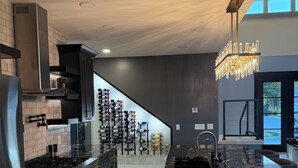 A modern kitchen with a marble island, stainless steel appliances, and a wine rack.