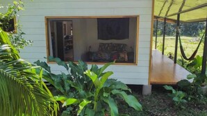 Ein kleines, eingeschossiges Haus mit einem großen Fenster und einer Hängematte davor.