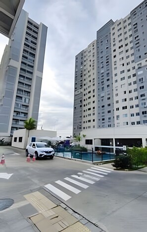 A multi-story residential building with a modern design, a pedestrian crossing, and a parking area with a white car. - 1503 Apto 2 Qtos completo João Pessoa (Cabedelo)
