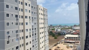 Um edifício alto com vários andares, janelas amplas e vista para o mar.