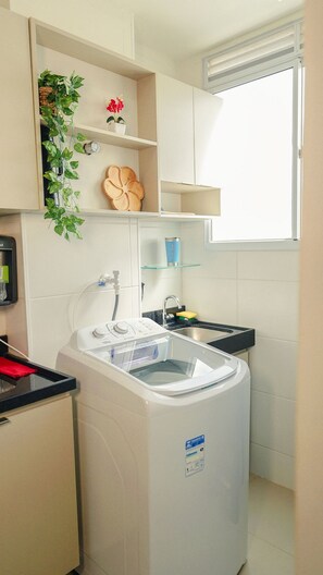 A compact kitchen with a built-in washing machine, a small sink, and a window. - 1503 Apto 2 Qtos completo João Pessoa (Cabedelo)